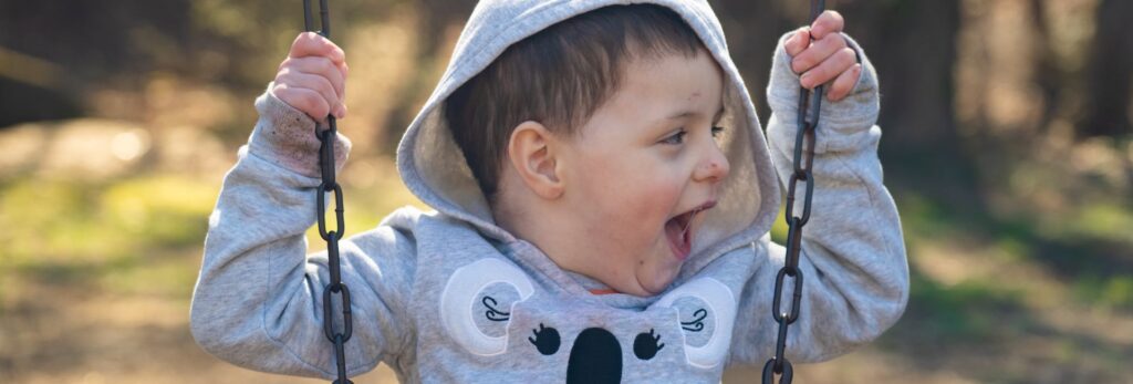 A child smiling while swinging on a swing set