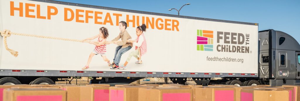 A feed the children semi in front of boxes at an event