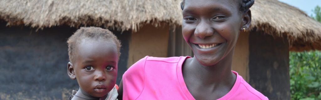 A mother holding her child smiling while outdoors