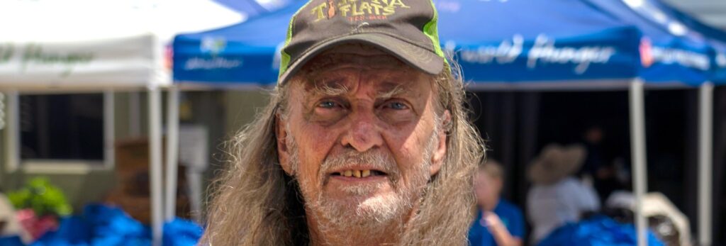 A man smiling outdoors at an event