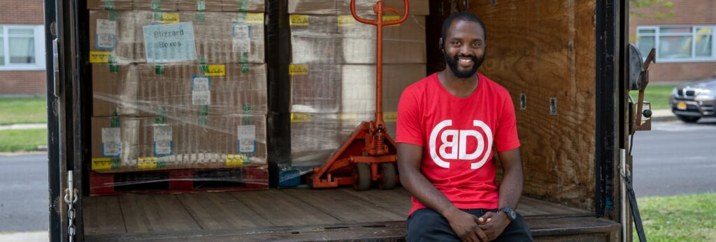 A man sitting on the back of a truck loaded with supplies