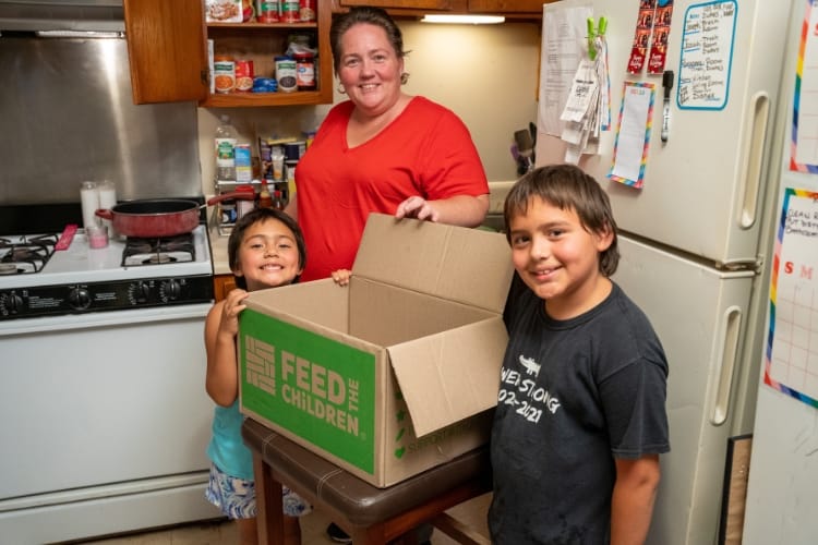 Katrina and her children with a box indoors