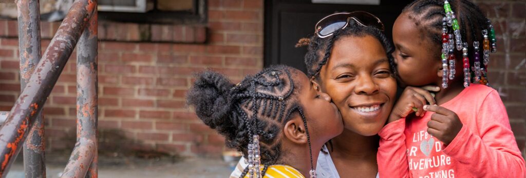 A mother with her two daughters smiling outdoors