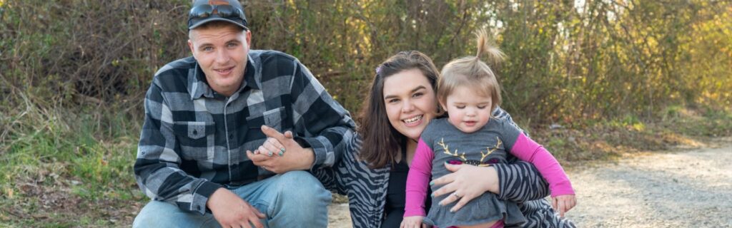 A family of three smiling outdoors