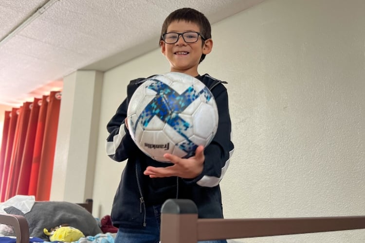 Lily's Son holding a ball in bed