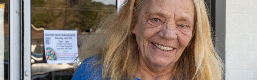 A woman smiling standing outside a door