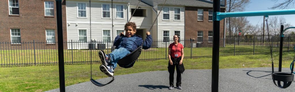 A boy swinging on a swing set with his mother