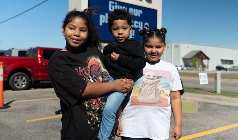 Three children standing in a parking lot at an event