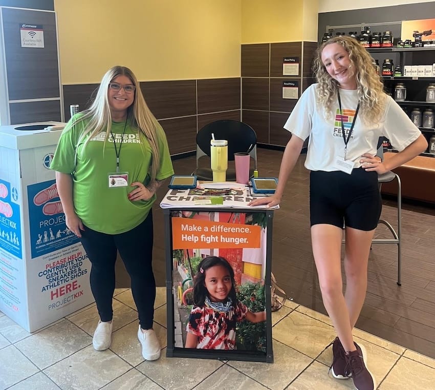 Two women standing next to a table volunteering