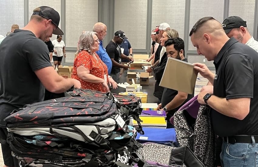 A group of volunteers helping fill backpacks at an event