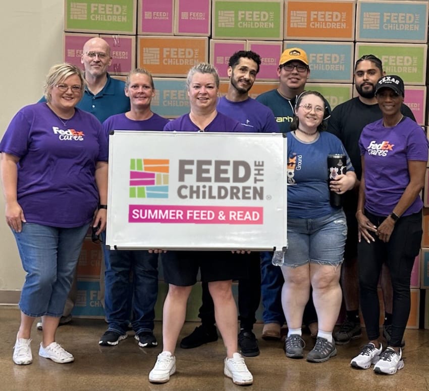 A group of people with a feed the children sign in front of boxes