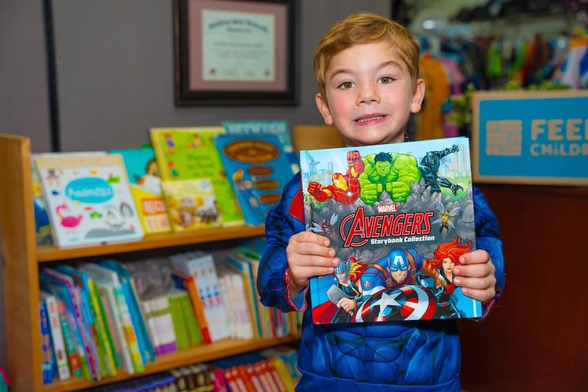 A child holding a book in front of a book shelf