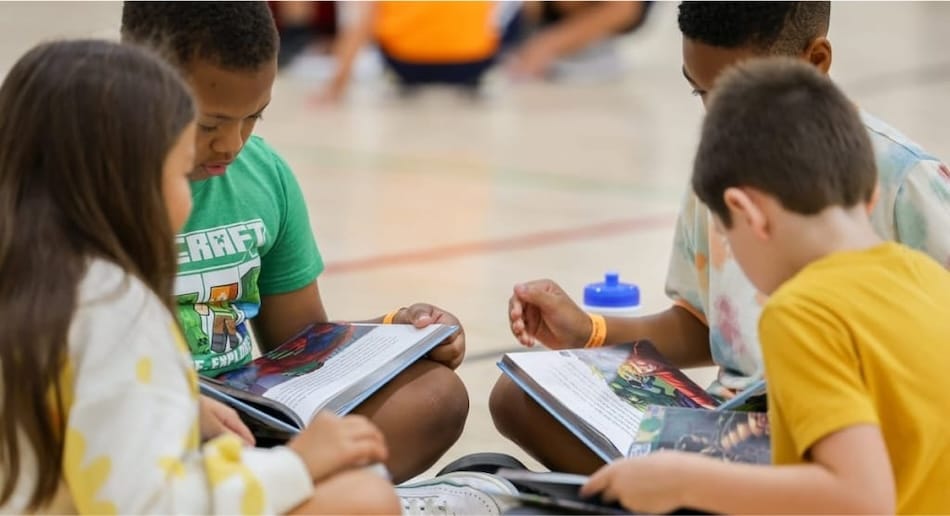 Children gathered together reading books in a school gym