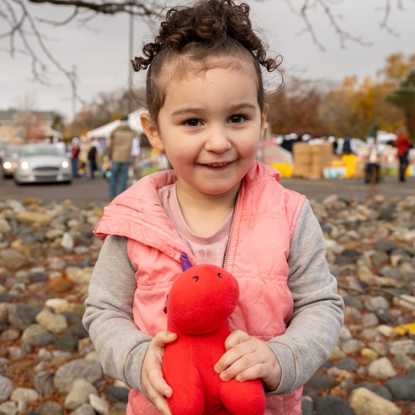 A child holding a stuffed animal outdoors at an event