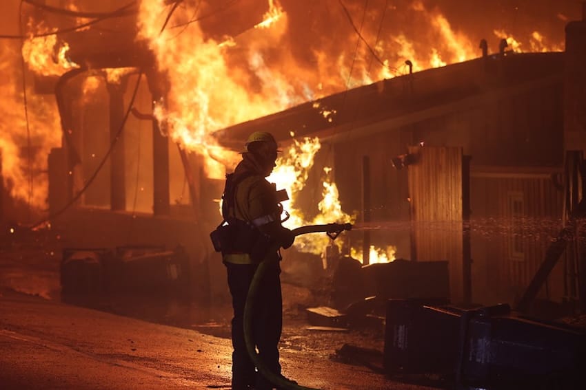 A Firefighter putting out a large fire with a water hose