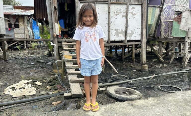 Maricel standing outdoors in front of a house