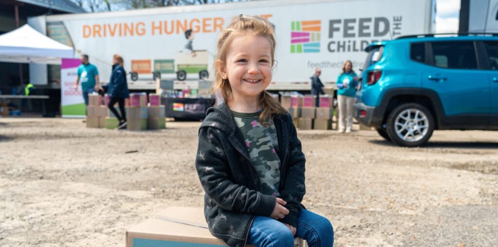 A child sitting on a box at an outdoor event