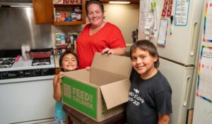 A woman and two children with a box in the kitchen